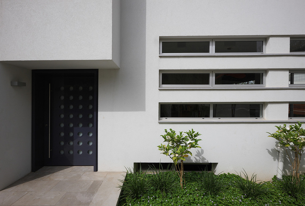 Réalisation d'une petite porte d'entrée minimaliste avec un mur blanc, un sol en calcaire et une porte simple.