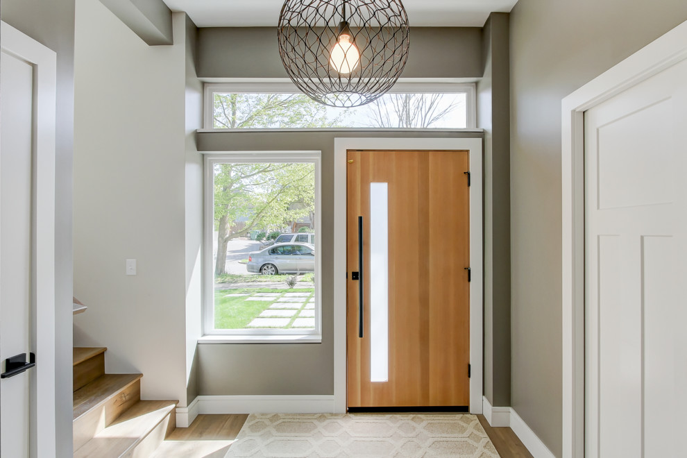 Foto de puerta principal contemporánea de tamaño medio con puerta simple, puerta de madera clara, paredes grises, suelo de madera en tonos medios y suelo marrón