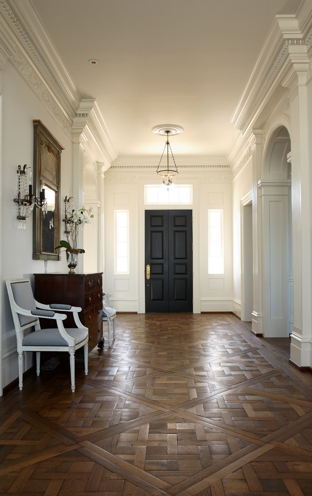 На фото: большая узкая прихожая в классическом стиле с белыми стенами, паркетным полом среднего тона и одностворчатой входной дверью с