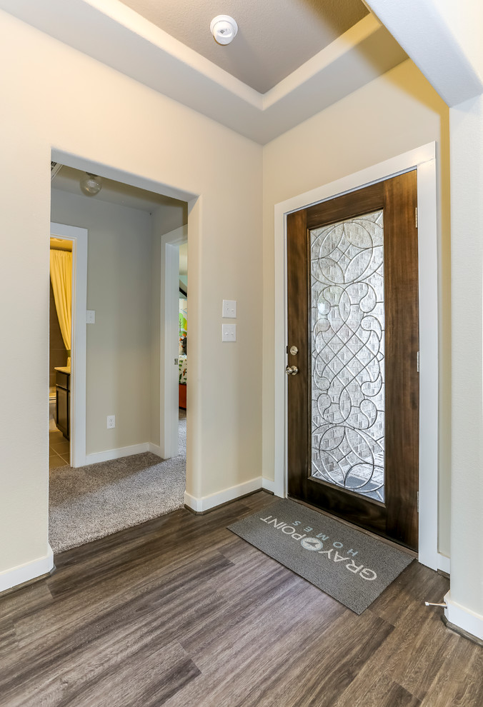 Ispirazione per un corridoio tradizionale di medie dimensioni con pareti beige, parquet scuro, una porta singola, una porta in vetro e pavimento marrone