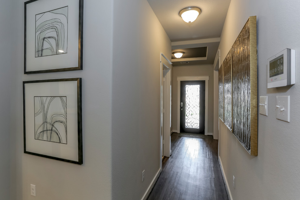 Esempio di un corridoio design di medie dimensioni con pareti beige, parquet scuro, una porta singola, una porta in vetro e pavimento marrone