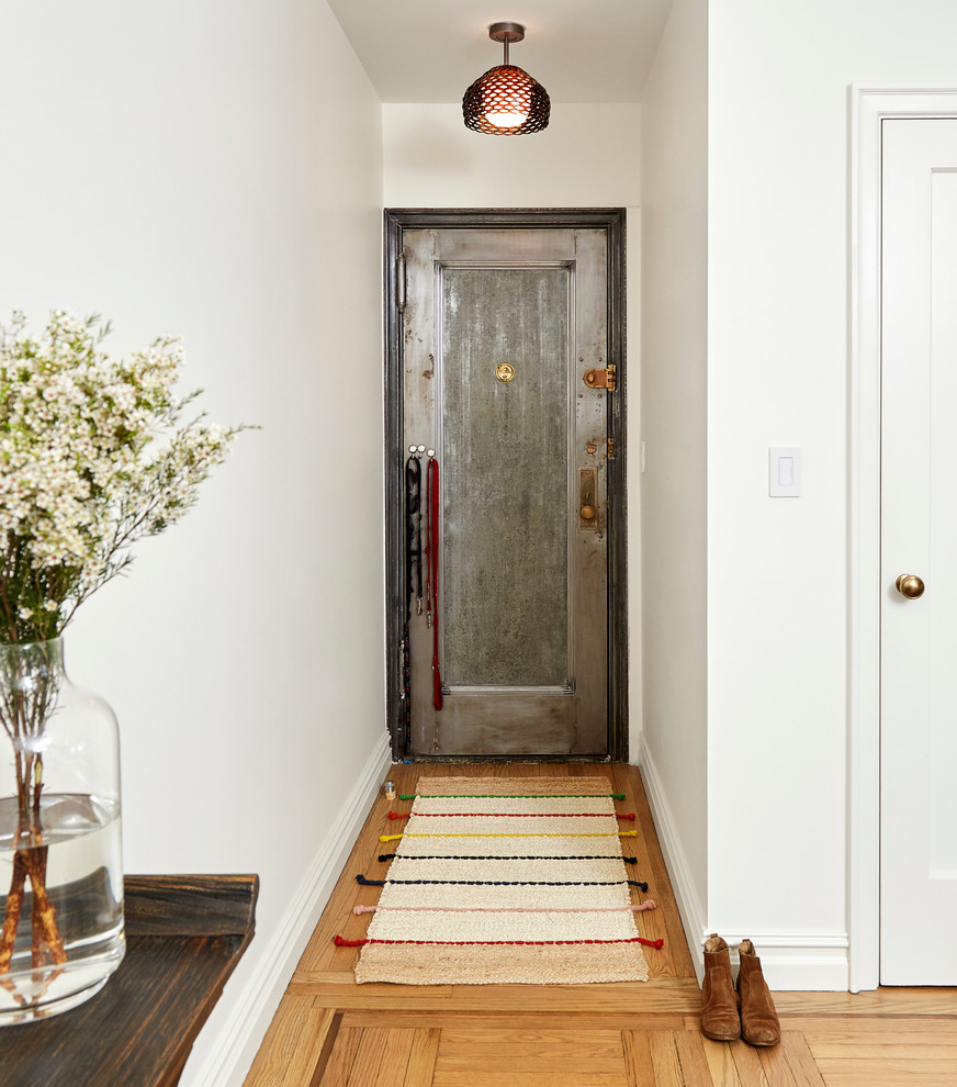 На фото: узкая прихожая среднего размера в современном стиле с белыми стенами, светлым паркетным полом, одностворчатой входной дверью и металлической входной дверью
