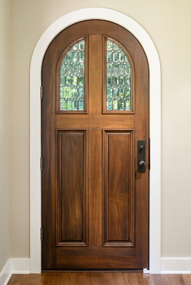 Cette photo montre une grande porte d'entrée chic avec un mur beige, un sol en bois brun, une porte simple, une porte en bois brun et un sol marron.