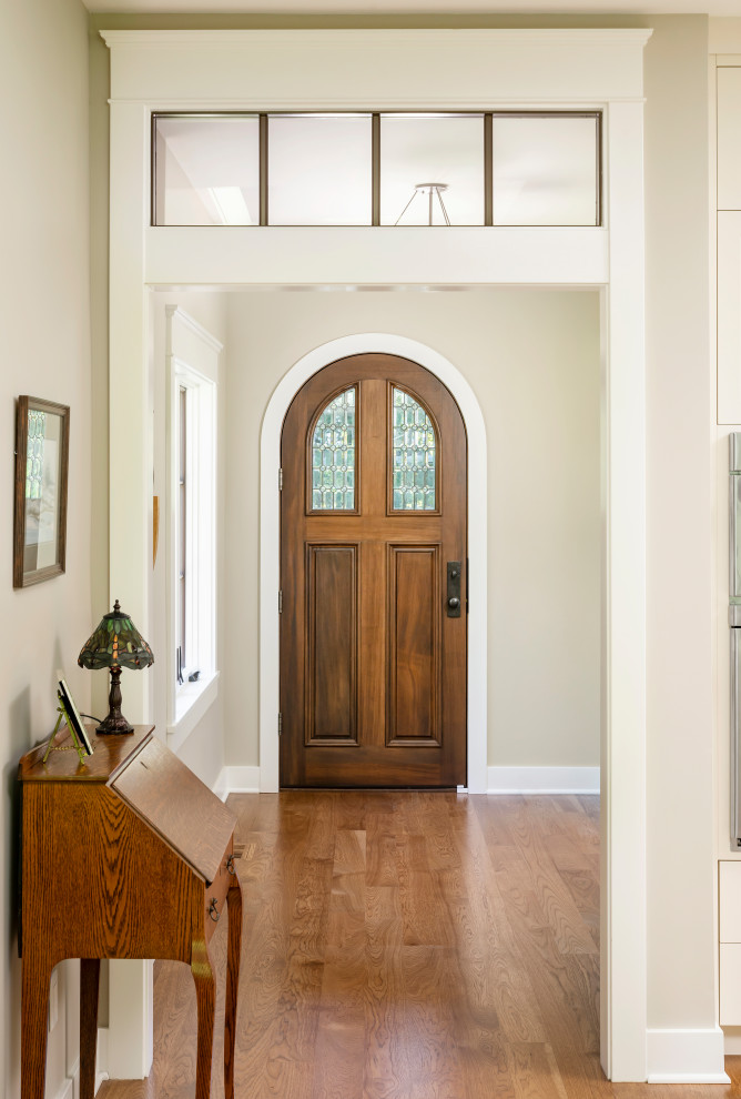 Exemple d'une grande porte d'entrée chic avec un mur beige, un sol en bois brun, une porte simple, une porte en bois brun et un sol marron.