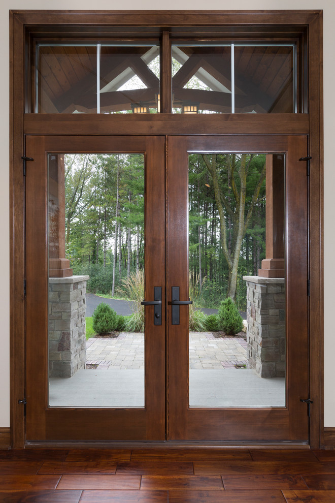 Idée de décoration pour une porte d'entrée chalet de taille moyenne avec un mur beige, un sol en bois brun, une porte double, une porte en bois foncé et un sol marron.