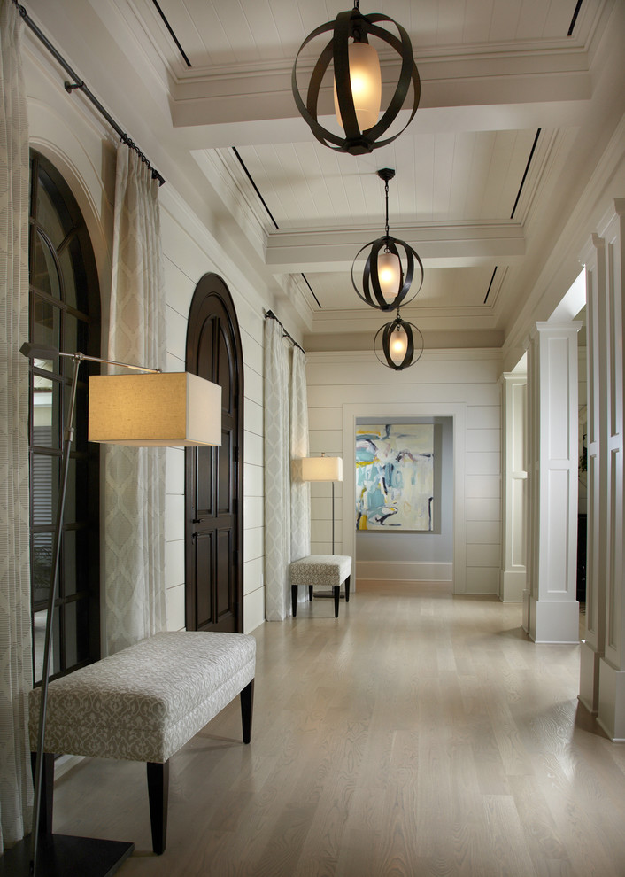 Пример оригинального дизайна: большое фойе: освещение в классическом стиле с белыми стенами, светлым паркетным полом, входной дверью из темного дерева и одностворчатой входной дверью