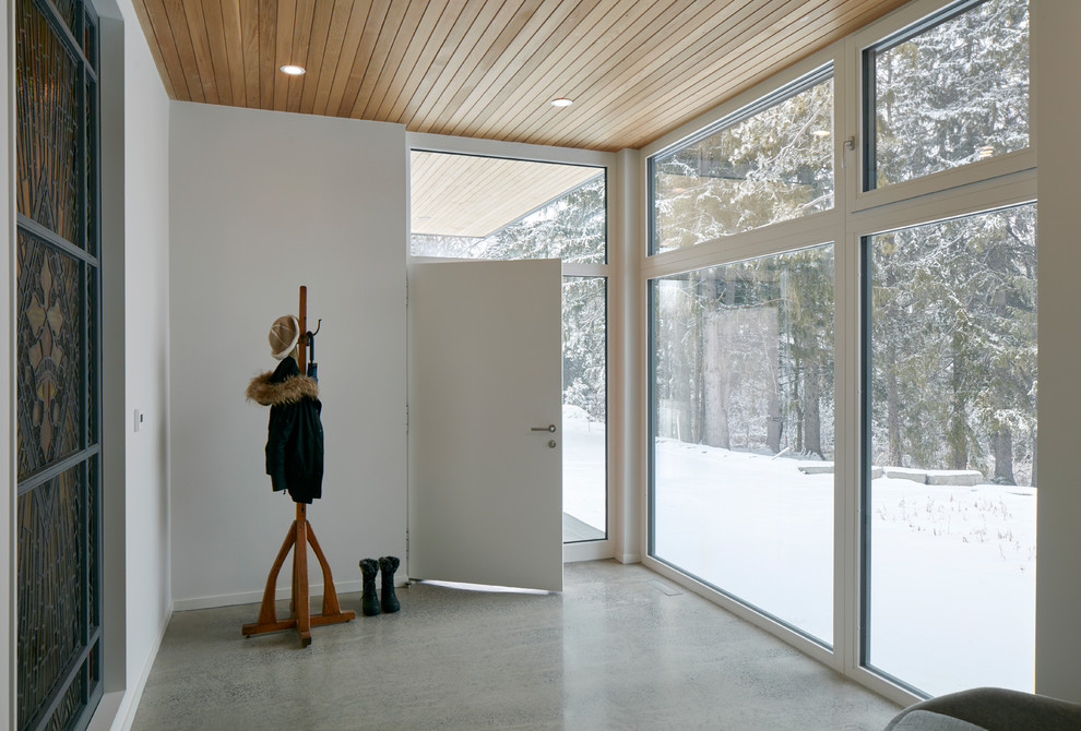 На фото: огромное фойе в стиле лофт с белыми стенами, бетонным полом, одностворчатой входной дверью, входной дверью из дерева среднего тона и серым полом