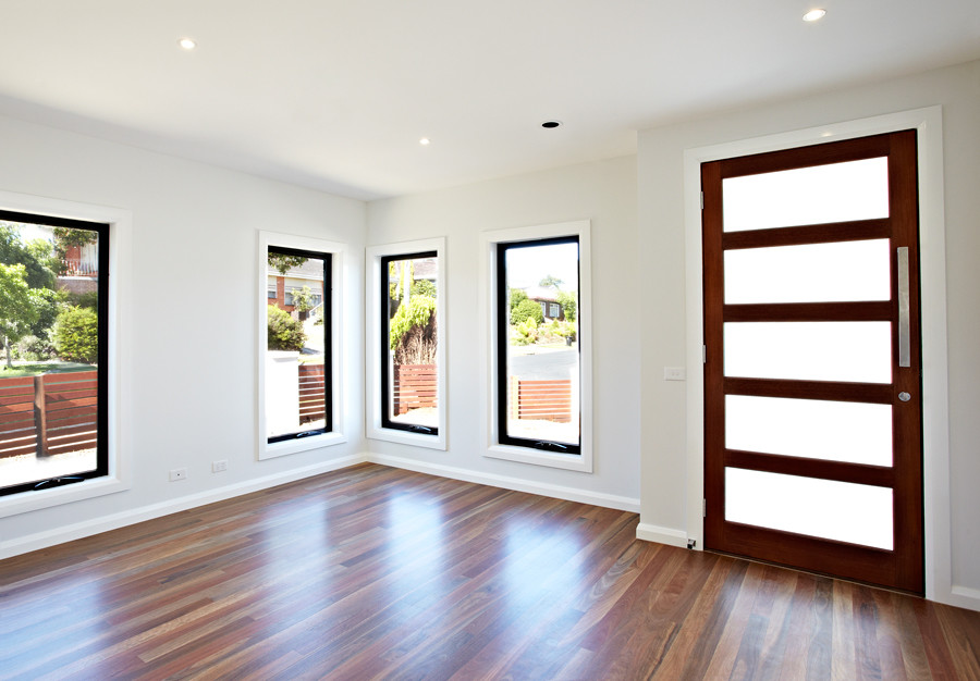Exempel på en mellanstor modern ingång och ytterdörr, med vita väggar, plywoodgolv, en enkeldörr, mörk trädörr och brunt golv