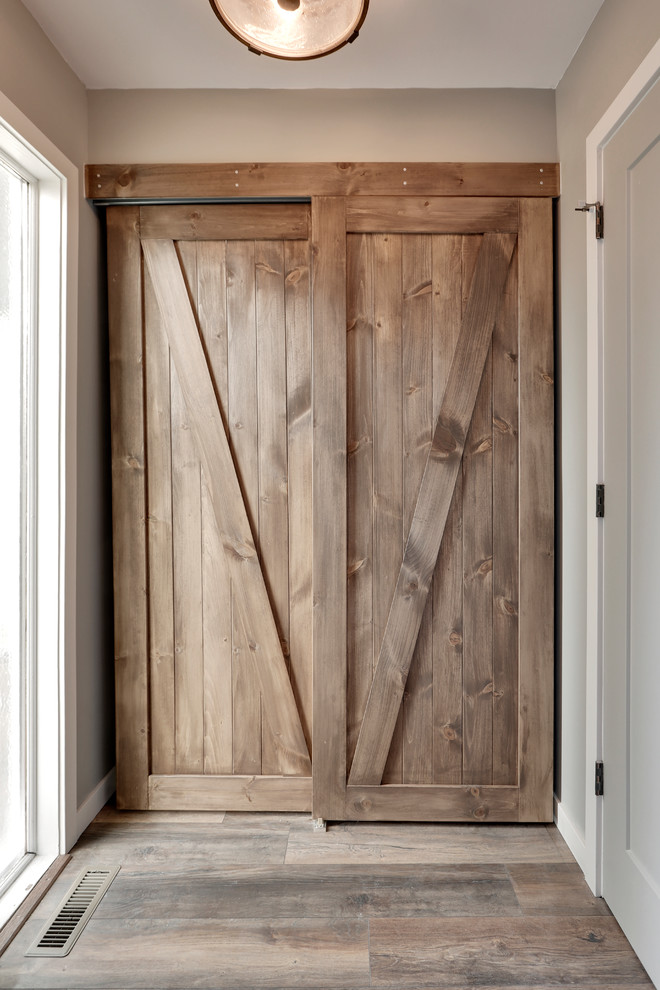Immagine di un piccolo ingresso con anticamera country con pareti grigie, pavimento in legno massello medio, una porta singola e una porta grigia