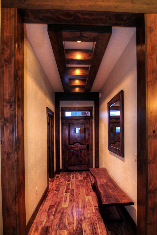 Réalisation d'une entrée craftsman de taille moyenne avec un couloir, un mur beige, un sol en bois brun, une porte simple et une porte en bois foncé.