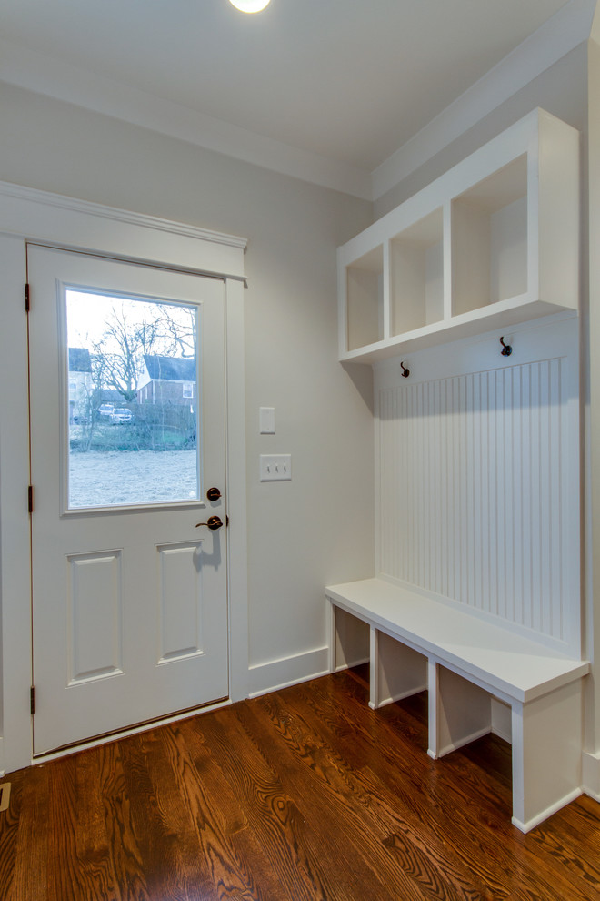 Exempel på ett mellanstort amerikanskt kapprum, med grå väggar, mörkt trägolv, en enkeldörr och en vit dörr