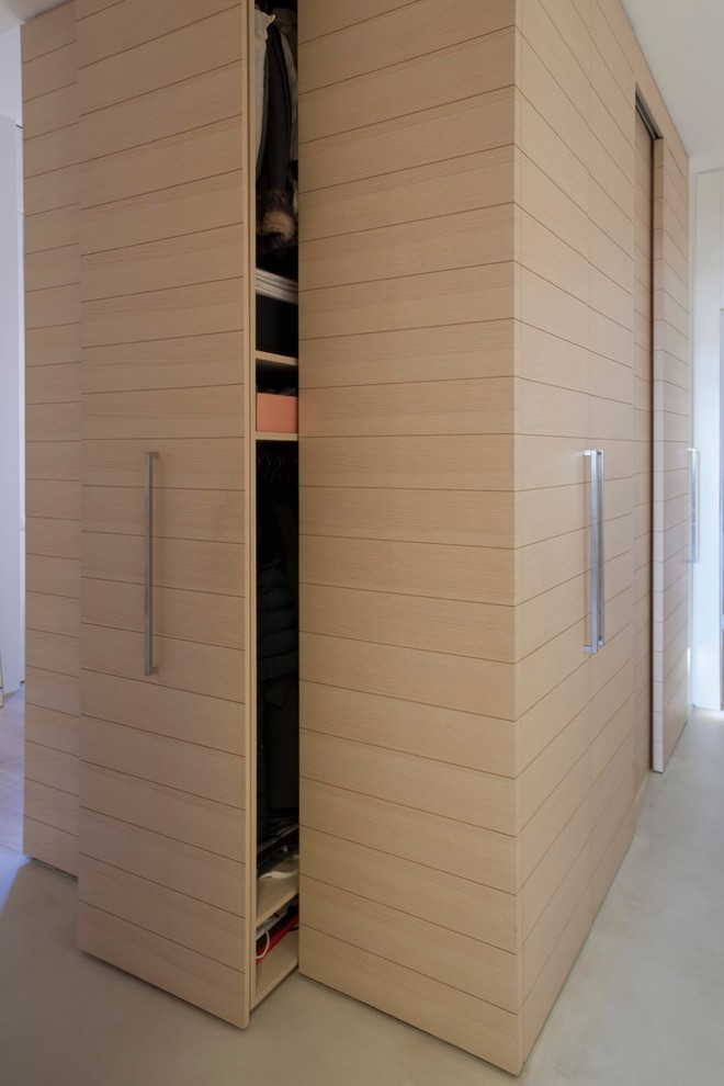 Ejemplo de entrada actual de tamaño medio con paredes blancas, suelo de cemento, suelo beige y puerta de madera clara