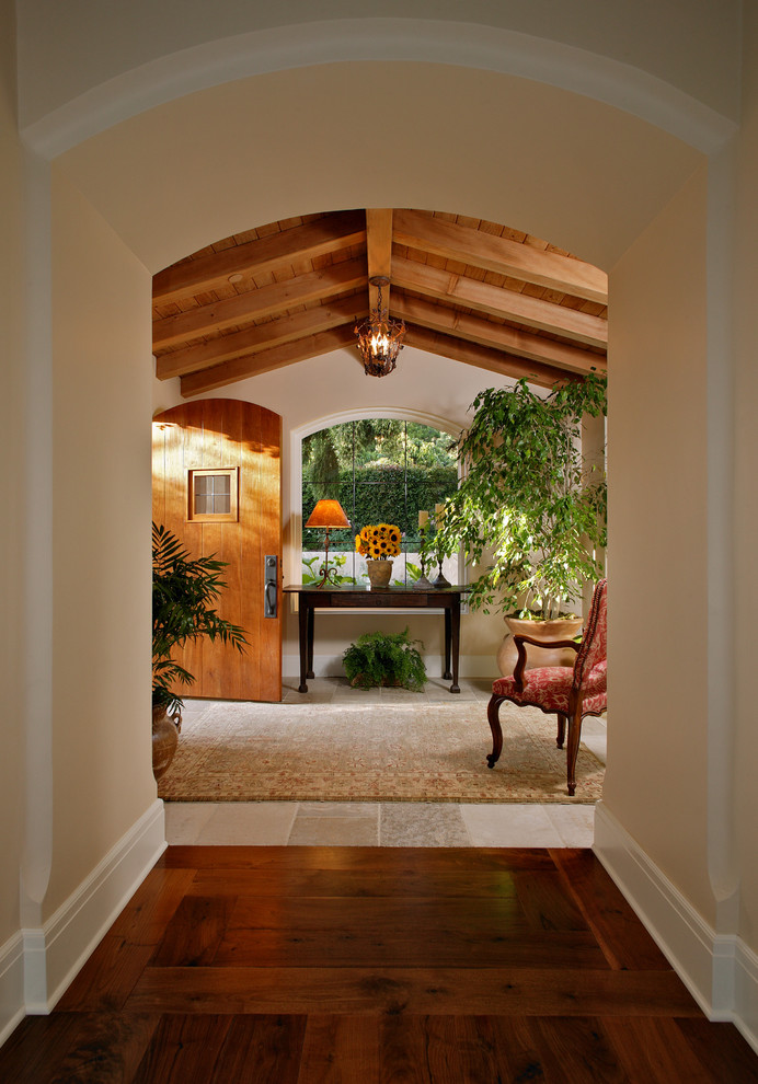 Mediterranean entrance in Santa Barbara with a single front door, a medium wood front door and beige floors.