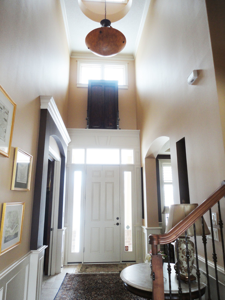 Пример оригинального дизайна: большое фойе в классическом стиле с бежевыми стенами, полом из травертина, одностворчатой входной дверью и белой входной дверью