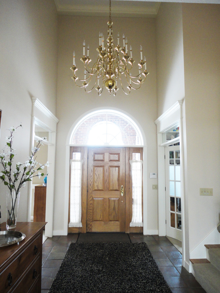 Modelo de puerta principal tradicional grande con paredes beige, suelo de baldosas de terracota, puerta simple y puerta de madera clara