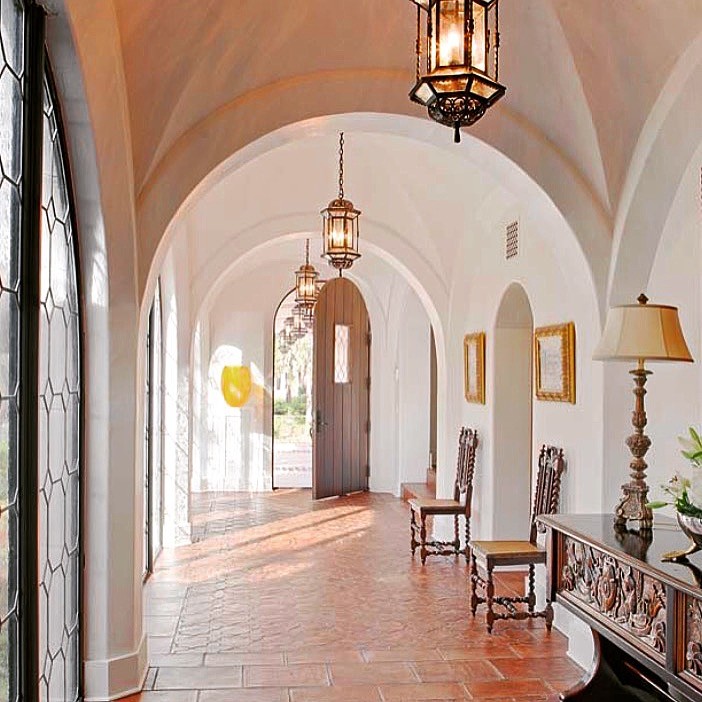 Example of a large tuscan terra-cotta tile and red floor entryway design in Atlanta with white walls and a medium wood front door
