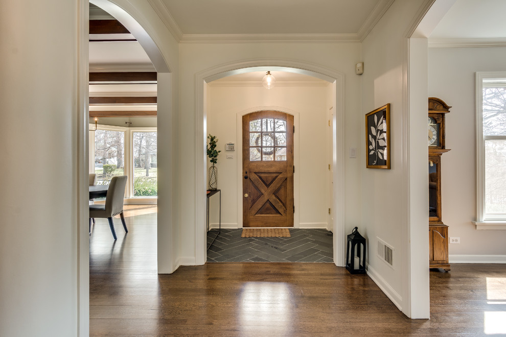 Aménagement d'une entrée classique avec un couloir, un mur blanc, un sol en bois brun, une porte simple, une porte en bois brun et un sol marron.