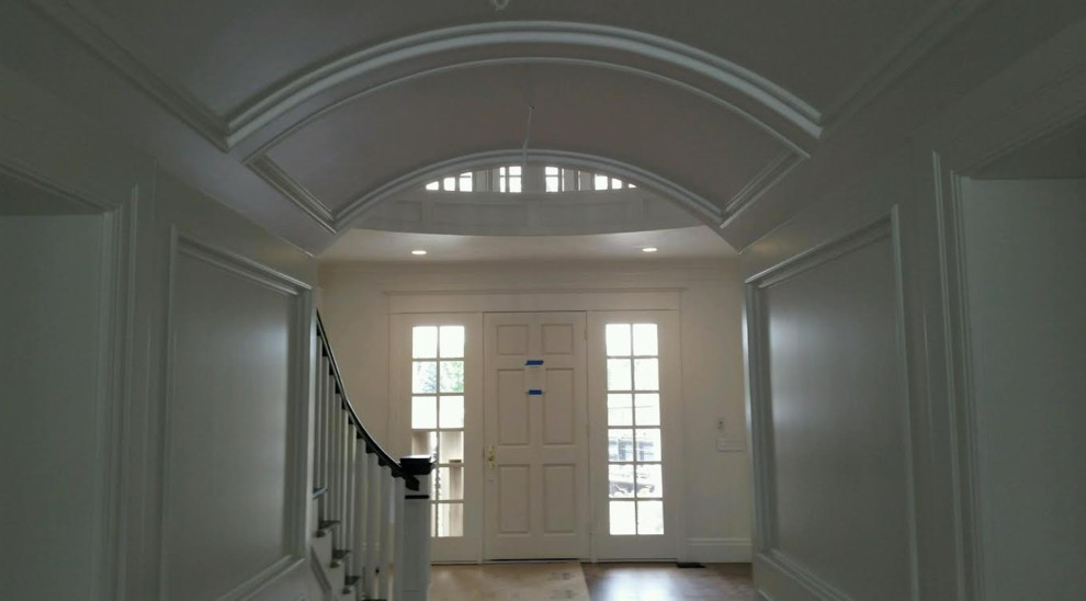 Exemple d'un hall d'entrée chic de taille moyenne avec un mur blanc, un sol en bois brun, une porte simple et une porte blanche.