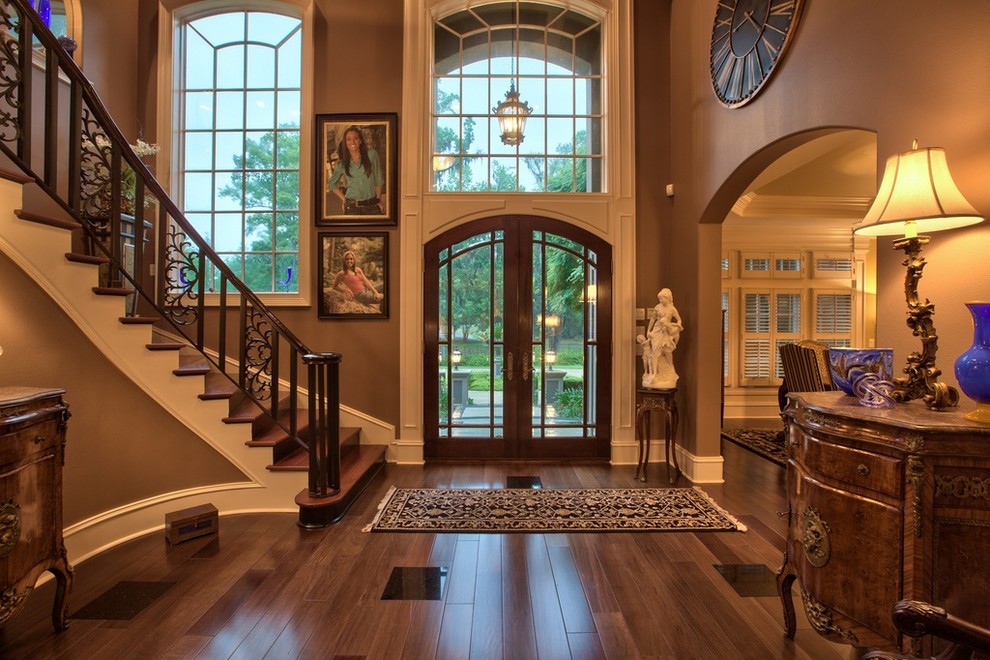 This is an example of an expansive traditional foyer in Miami with brown walls, dark hardwood flooring, a double front door and a dark wood front door.