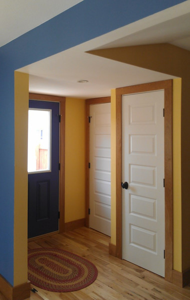 Cette photo montre une entrée éclectique de taille moyenne avec un vestiaire, un mur jaune, un sol en bois brun, une porte simple et une porte bleue.