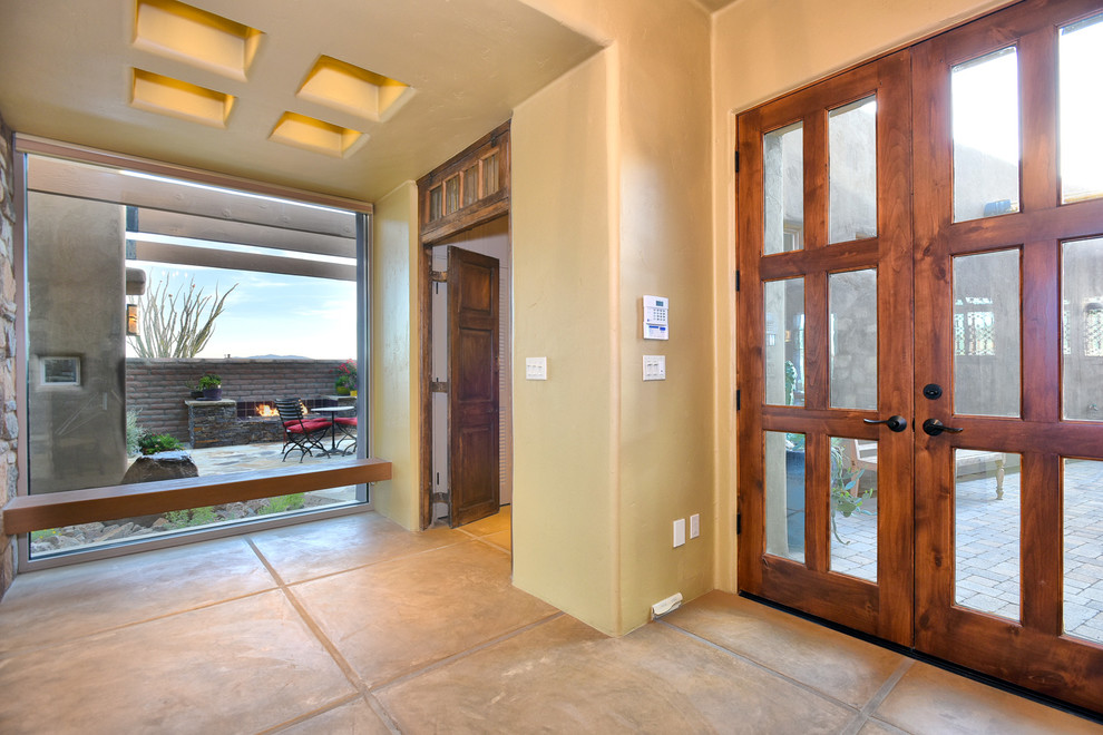 Cette photo montre une grande porte d'entrée tendance avec un mur beige, tomettes au sol, une porte double et une porte en bois foncé.