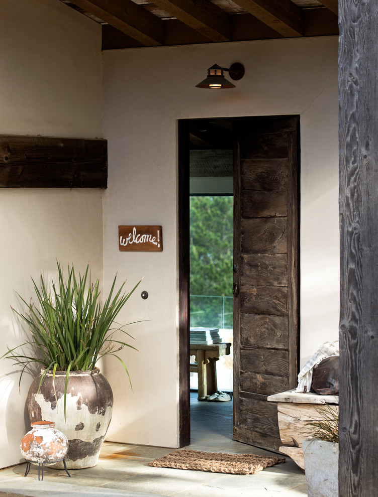 Modelo de puerta principal rural con paredes blancas, puerta simple, puerta de madera oscura y suelo gris