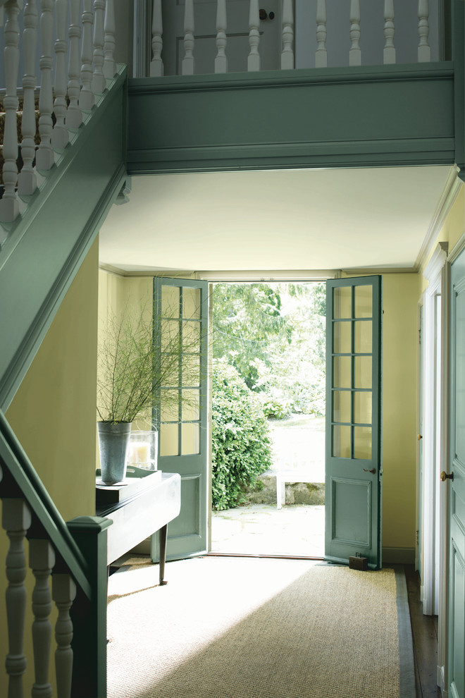 Aménagement d'un hall d'entrée romantique de taille moyenne avec un mur jaune, parquet foncé, une porte double, une porte bleue et un sol marron.