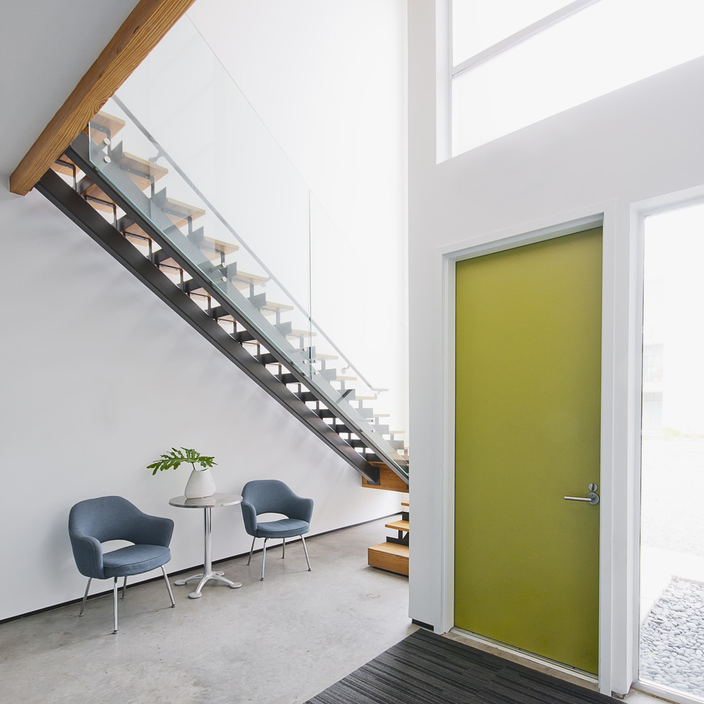 Imagen de entrada minimalista con puerta verde y suelo gris