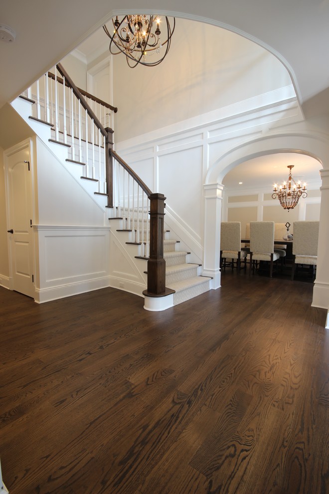 This is an example of a large traditional foyer in New York with dark hardwood flooring, a double front door, a dark wood front door and white walls.