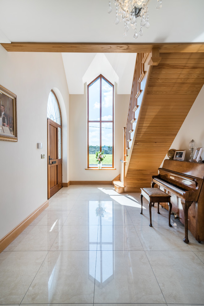 Ejemplo de hall clásico grande con puerta simple, puerta de madera en tonos medios, suelo de baldosas de porcelana, paredes beige y suelo blanco