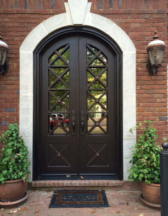 Cette image montre une grande porte d'entrée traditionnelle avec une porte double et une porte métallisée.