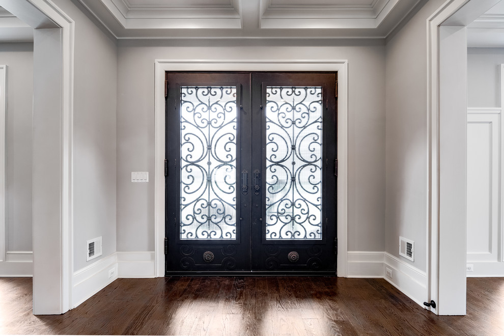 Cette image montre une porte d'entrée traditionnelle de taille moyenne avec un mur gris, un sol en bois brun, une porte double, une porte métallisée et un sol marron.