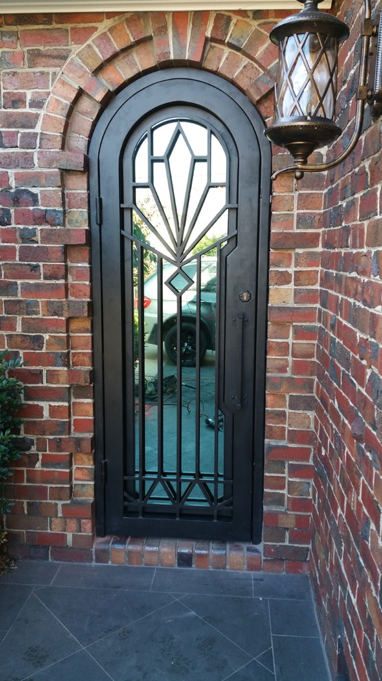 Стильный дизайн: входная дверь с красными стенами, полом из сланца, одностворчатой входной дверью, металлической входной дверью и черным полом - последний тренд