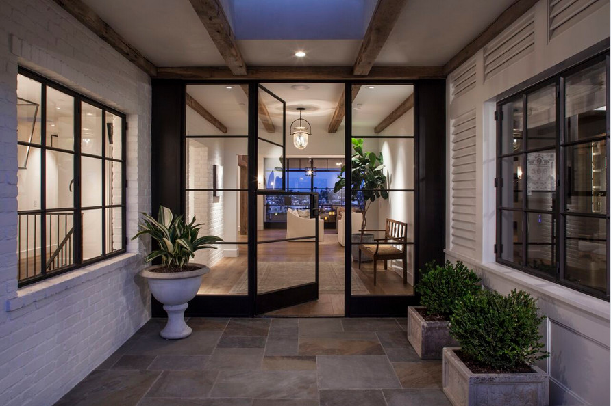 Design ideas for a large mediterranean front door in Orange County with white walls, travertine flooring, a stable front door and a dark wood front door.