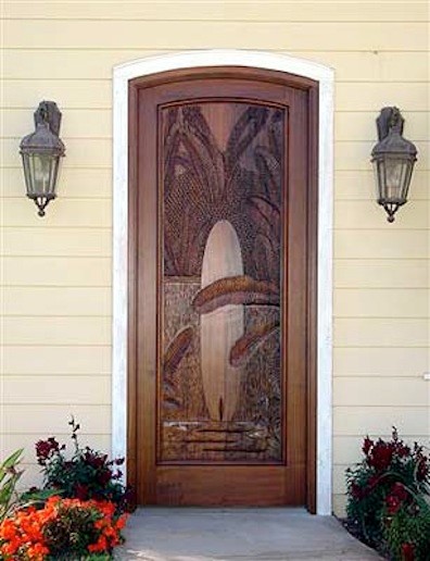 Example of an island style medium tone wood floor entryway design in San Diego with a medium wood front door and beige walls