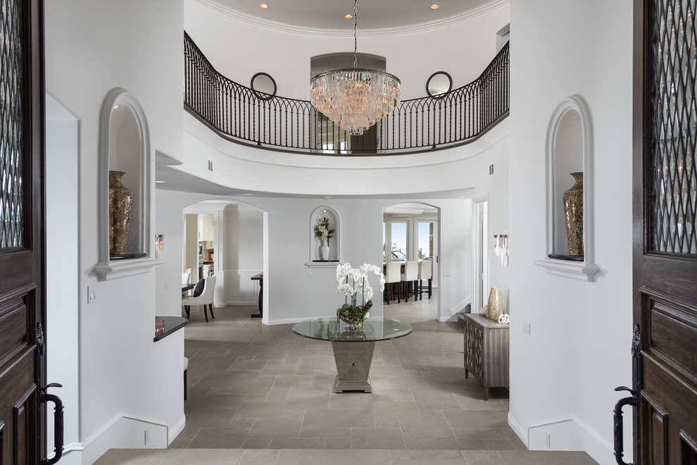 Example of a tuscan gray floor entryway design in Orange County with white walls and a dark wood front door