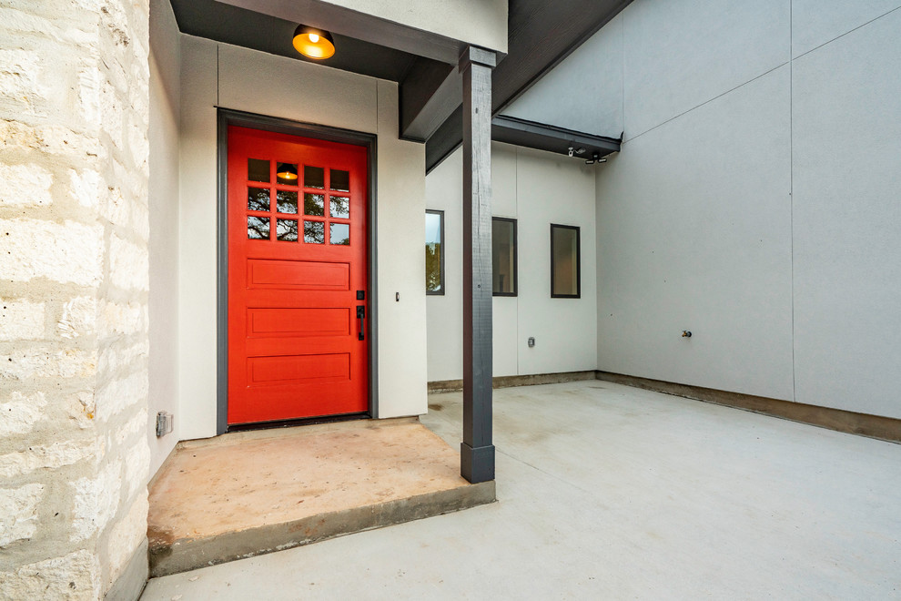 Immagine di una porta d'ingresso country di medie dimensioni con pareti bianche, pavimento in cemento, una porta singola, una porta rossa e pavimento grigio