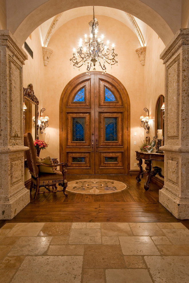 На фото: огромная входная дверь в средиземноморском стиле с бежевыми стенами, паркетным полом среднего тона, двустворчатой входной дверью и входной дверью из дерева среднего тона