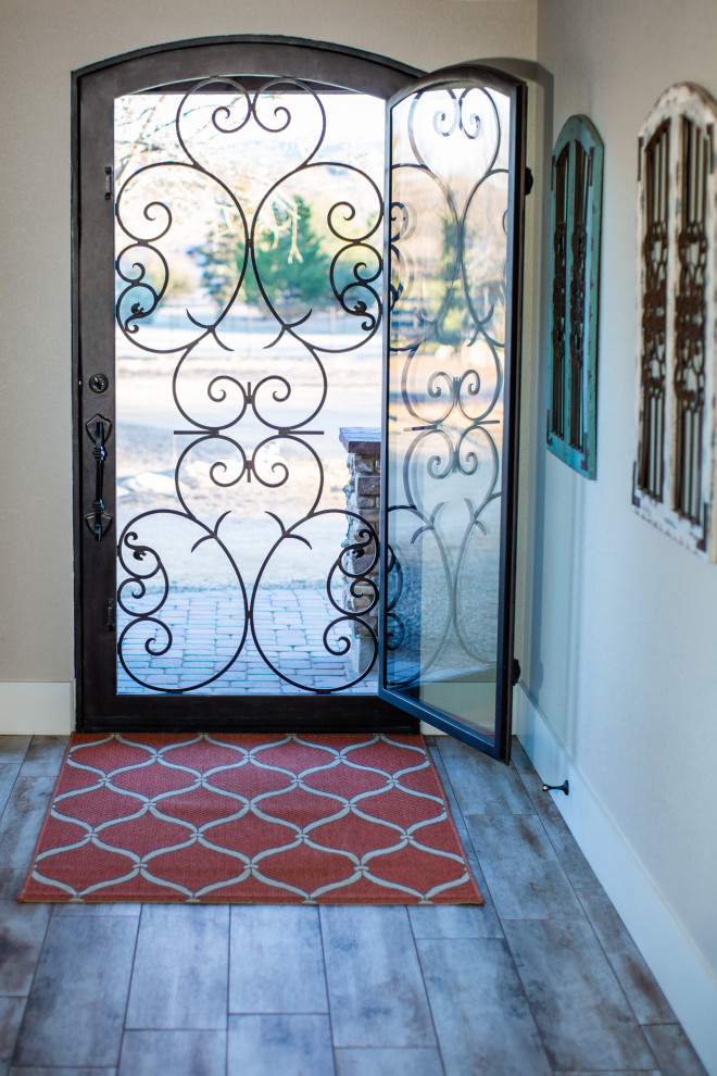 フェニックスにある高級な広いラスティックスタイルのおしゃれな玄関ロビー (ベージュの壁、磁器タイルの床、茶色いドア、ベージュの床) の写真
