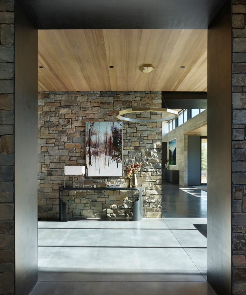 Großes Rustikales Foyer mit bunten Wänden, Betonboden, grauem Boden, Holzdecke und Ziegelwänden in Sonstige