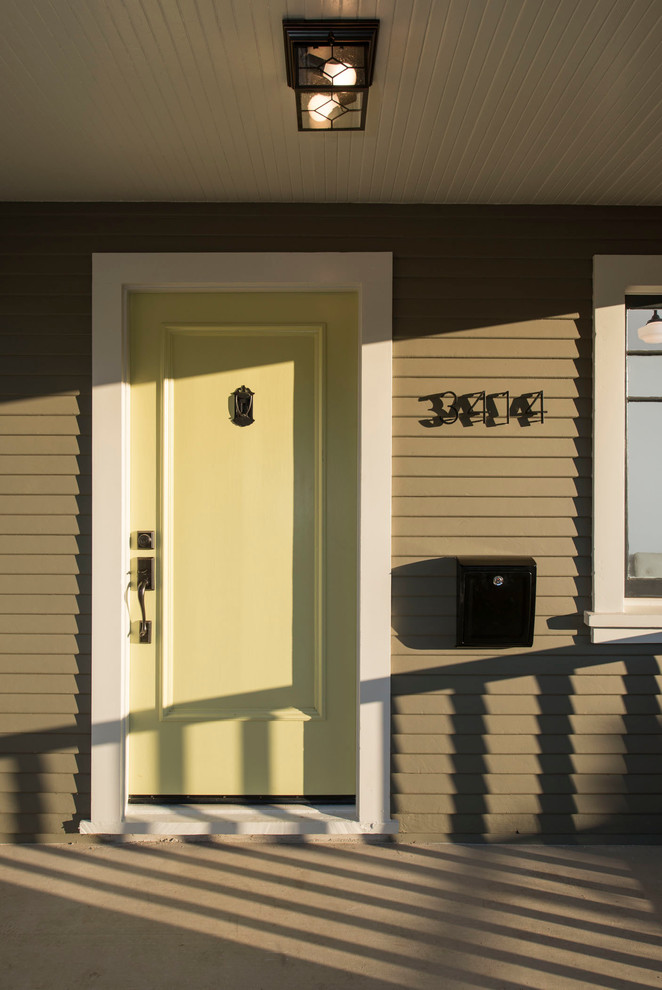 Immagine di una porta d'ingresso american style di medie dimensioni con pareti verdi, pavimento in cemento, una porta singola e una porta gialla