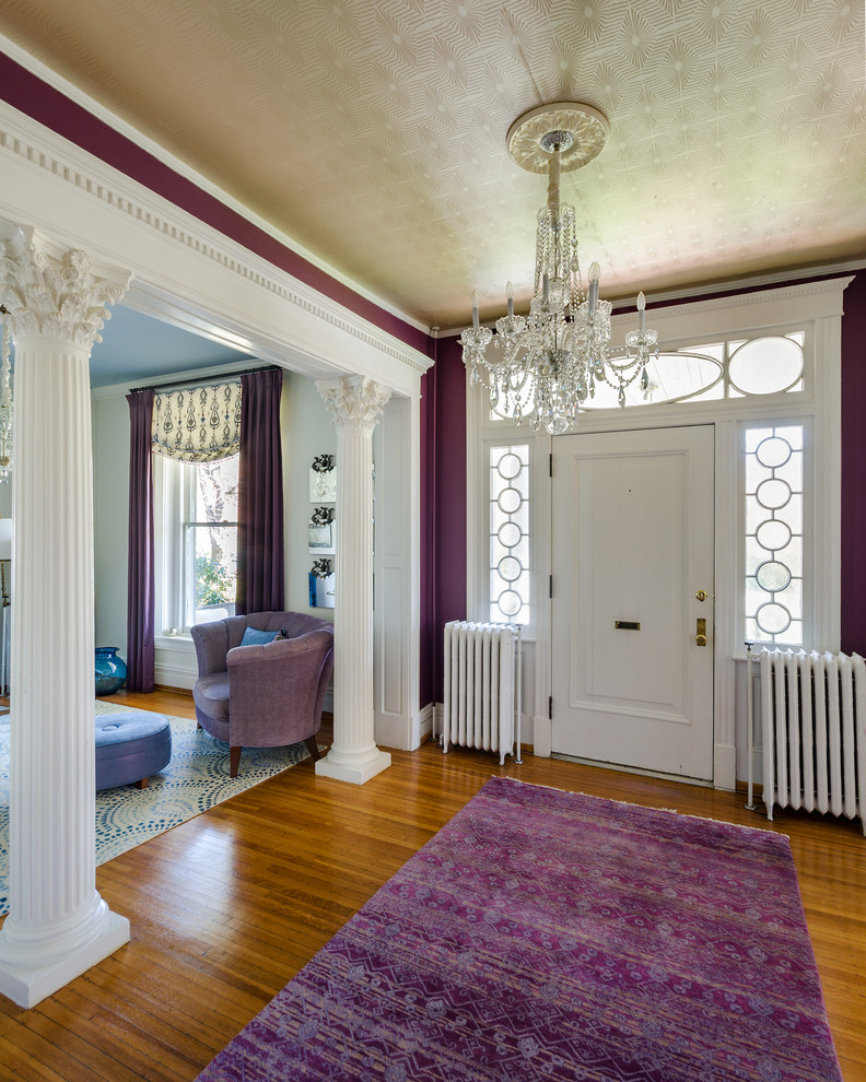 Inspiration pour un hall d'entrée traditionnel avec un mur violet, un sol en bois brun, une porte simple, une porte blanche et un sol marron.
