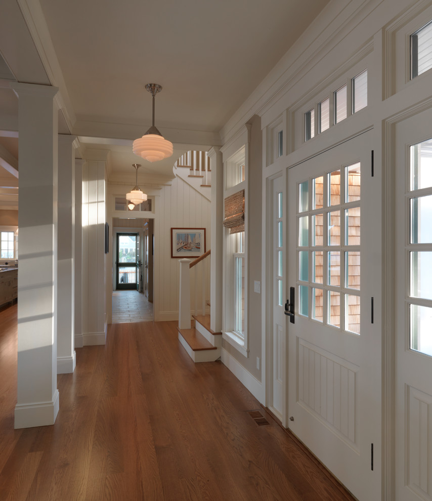Cette photo montre un hall d'entrée chic avec un mur blanc, un sol en bois brun, une porte simple et une porte blanche.
