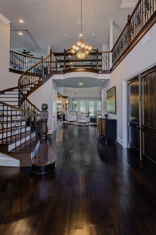 This is an example of an expansive traditional foyer in Dallas with grey walls, dark hardwood flooring and a glass front door.
