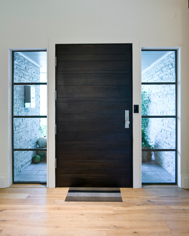 На фото: входная дверь среднего размера в современном стиле с белыми стенами, светлым паркетным полом, одностворчатой входной дверью и входной дверью из темного дерева