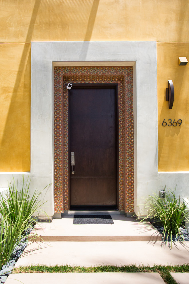 Foto de puerta principal contemporánea con paredes amarillas, suelo de cemento, puerta simple y puerta de madera oscura