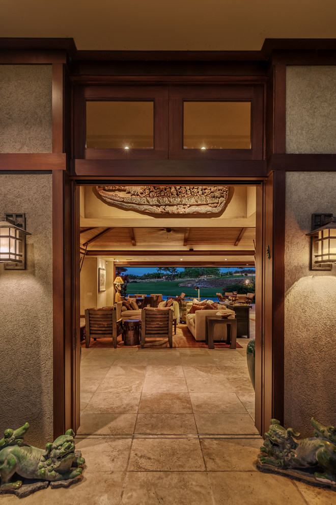 Example of a large island style entryway design in Hawaii with beige walls and a dark wood front door