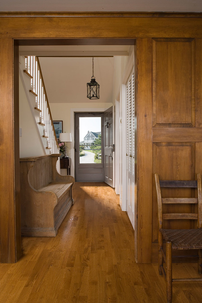 Foto di un corridoio american style di medie dimensioni con pareti beige, pavimento in legno massello medio, una porta singola e una porta grigia