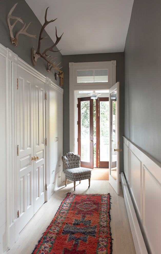 Cette photo montre un vestibule chic avec un mur gris, parquet clair, une porte double, une porte en verre et un sol beige.