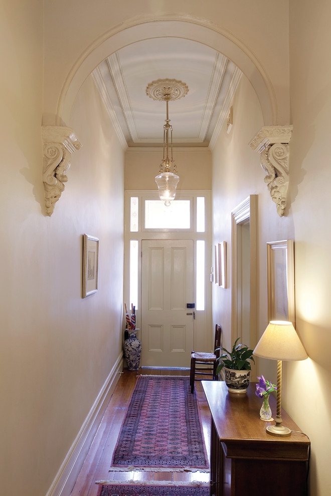 Imagen de puerta principal clásica pequeña con paredes blancas, puerta simple, puerta blanca y suelo de madera en tonos medios